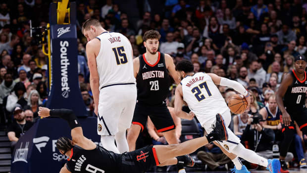 Rockets forward Dillon Brooks falls to the court after colliding with Nuggets center Nikola Jokic as he screens for guard Jamal Murray.